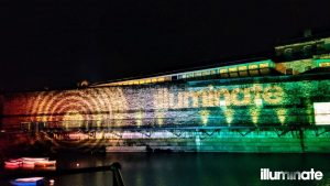 Illuminate logo projected onto uplit exterior wall